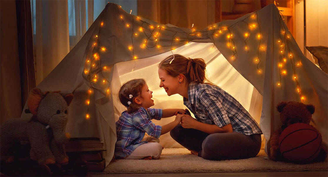 mère et fils souriants, sous une tente dans la maison